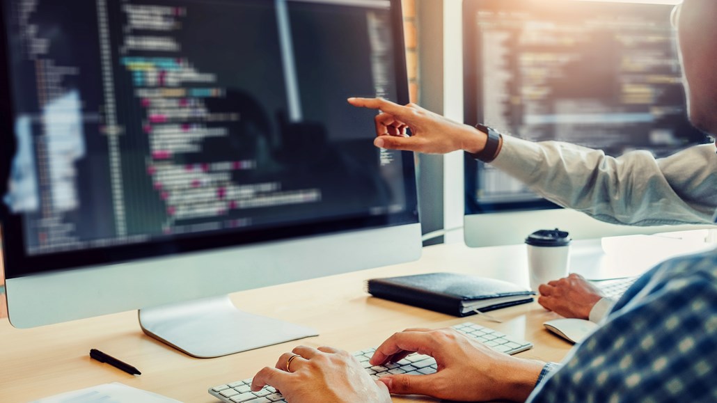 两个人看着电脑显示器，一个人指着屏幕